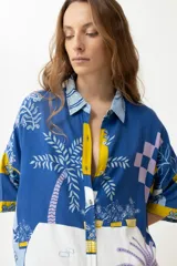 Vestido camisero corto con estampado de paisaje en tonos azules y amarillos.