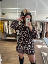 Vestido corto con estampado animal print, de mangas largas traslúcidas y falda con volados.