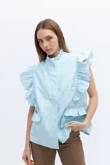 Chaleco celeste de lino con cuello mao, cierre frontal con botones y volados en hombros y bolsillos.