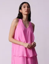 Vestido corto de gasa color fucsia, con escote en V y capas superpuestas. Incluye forro interno a tono.