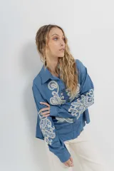 Camisa de denim azul con bordados en color crudo, de corte relaxed, manga larga y botones frontales.