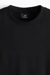 Remera negra de punto de algodón liviano, de corte estándar, con cuello redondo ribeteado y bajo recto.