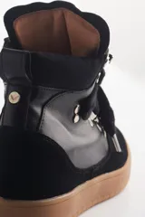 Zapatilla urbana negra de caña alta con plataforma, cordones y detalles de cuero y gamuza.