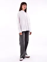 Camisa blanca con detalle de frunces en el cuello y puños, de corte clásico y mangas largas.