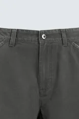 Pantalón de algodón color gris oscuro con efecto lavado, corte relaxed fit y pierna ancha. Presenta bolsillos delanteros, bolsillos traseros de plastrón y un bolsillo lateral con cierre de cremallera en la pierna.