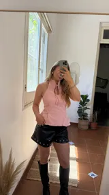 Top rosa de gabardina elastizada, con cuello halter, sin mangas, con tiras para atar en la parte delantera y ajuste con tiras en la parte trasera.