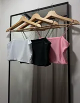 Top de tirantes finos, corte recto y confeccionado en tejido liso.