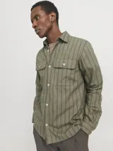 Sobrecamisa de manga larga color verde oliva con rayas verticales finas en tono más claro. Tiene cuello clásico, cierre con botones, dos bolsillos en el pecho con cierre de botón y puños abotonados. Corte recto y cómodo. Confeccionada en tejido de sarga de algodón y lino.