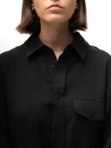 Camisa negra de lino con mangas 3/4, bolsillo en el lado izquierdo y pliegue en la espalda.