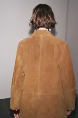 Blazer de cuero color marrón, con cuello solapa de muescas y manga larga. Bolsillos delanteros ocultos en costura y cierre frontal con botones.