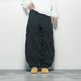 Pantalón de jean negro de corte ancho, con detalles de flecos diagonales en la parte delantera.