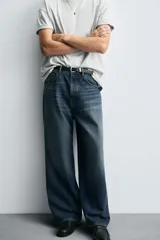 Pantalón de jeans de algodón, corte baggy fit, tiro medio, con efecto lavado en tonos grises y verdes. Presenta cinco bolsillos y cierre frontal con cremallera y botón.