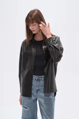 Sobrecamisa negra de efecto cuero, con cuello camisero, botones frontales y dos bolsillos de parche con solapa en el pecho. Presenta un calce holgado.