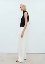 Pantalón de jeans estilo wideleg, color blanco crudo, tiro medio, con cierre de botón y cremallera, y detalle de pinzas delanteras.