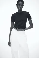 Remera negra entallada de punto de algodón elástico, con cuello redondo fino ribeteado y bajo recto.