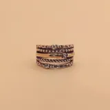 Anillo ancho de plata con detalles en oro y circonias. Diseño con múltiples bandas de diferentes texturas y detalles, incluyendo una banda trenzada y otra con pequeñas esferas.