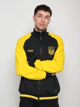 Campera deportiva de felpa negra con mangas amarillas en contraste y escudo del Club Atlético Peñarol estampado en el pecho.