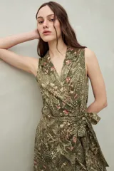 Vestido midi sin mangas con estampado floral y de hojas en tonos verde y marrón. Diseño cruzado tipo wrap con cuello sastrero y lazo ajustable en la cintura.