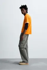 Camiseta naranja de algodón con cuello redondo y manga corta con vuelta. Estampado frontal con la firma del artista Otis Kwame Kye Quaicoe.