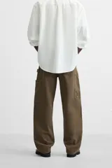 Pantalón color verde oliva de corte recto, confeccionado en algodón. Cuenta con bolsillos frontales, traseros y laterales tipo cargo, además de una tira multifunción.