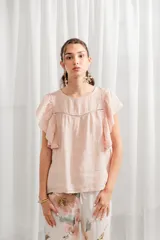 Blusa color rosa pálido de lino con volados en las mangas, corte ancho, cuello redondo y detalle de calado en el canesú.