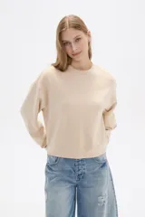 Buzo color beige de corte ancho y cuello redondo.