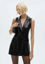 Mono corto negro con lentejuelas, cuello con solapa, sin mangas y bolsillos de ribete.