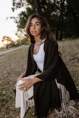 Ruana color chocolate de lana merino, con flecos en el borde inferior.