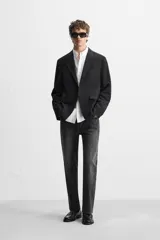 Pantalón de jean negro con efecto lavado, corte slim fit, cinco bolsillos y cierre frontal con botones.
