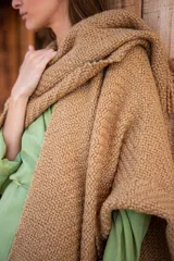 Ruana color camel de tejido de punto grueso con flecos en el borde inferior.