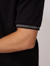 Remera polo negra de corte regular, con cuello y mangas con rayas en contraste blancas y logo bordado en el pecho.