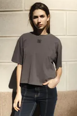 Remera negra de algodón con corte cuadrado, cuello redondo y logo bordado en color naranja.