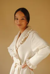 Bata larga color blanco, confeccionada en algodón capitoneado con diseño de espiga. Presenta volados en el cuello y puños, y lazo de ajuste en la cintura.