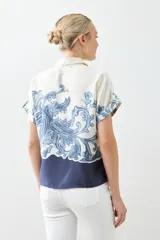 Camisa de manga corta con estampado paisley en tonos azul y blanco, con cuello clásico y cierre con botones.