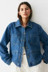 Campera azul de denim con cuello clásico, cierre frontal con botones dorados, dos bolsillos de parche en el pecho y dos bolsillos ribeteados en la cintura.