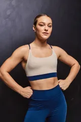 Top deportivo color beige con banda inferior azul y tirantes finos azul marino. Espalda cruzada con doble tira.