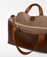 Bolso tipo tote grande color marrón, con doble asa de mano y correa larga extraíble. Interior con dos compartimentos y bolsillo central con cierre.