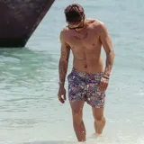 Short de baño con estampado floral en tonos violeta, azul y blanco. Cuenta con pretina fija con hebillas metálicas laterales, botón a presión, cierre frontal, tres bolsillos y mesh interior hipoalergénico.