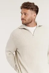 Sweater de punto color crema con cuello alto y cierre de cremallera parcial. Diseño de corte holgado y mangas largas.