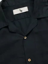 Camisa de manga corta color crema, con cuello camp y calce relajado. Confeccionada en una mezcla de lino y algodón, con botones de madera y parche característico de Polonio.