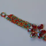 Pulsera artesanal de diseño vibrante, con cristales de vidrio y piedras de colores en forma de lágrima formando un patrón floral.