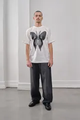 Remera negra oversize de algodón con estampado de mariposa plateada.