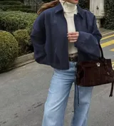 Chaqueta tipo bomber de gamuza azul marino, con cuello camisero, cierre frontal y mangas amplias, de corte a la cintura.