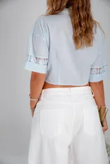 Camisa celeste corta con broderie y nudo delantero.