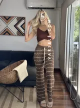 Pantalón de hilo color marrón con rayas horizontales blancas, corte holgado y cintura con cordón ajustable.