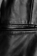 Blazer de cuero negro con cuello solapa de muescas y manga larga. Tiene bolsillos de vivo en el delantero, forro interior a tono y cierre frontal con botones.