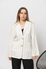 Blazer blanco con rayas verticales negras, de corte recto, con cuello de solapa, bolsillos frontales y cierre con doble botón de madera.