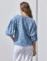 Blusa celeste con estampado floral blanco, escote en V y botones. Mangas 3/4 abullonadas con terminación elastizada.