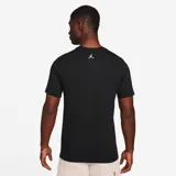 Camiseta negra de algodón con cuello redondo y manga corta. Estampado frontal con el logo de Jordan en color crema y efecto de movimiento.