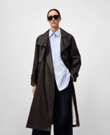 Gabardina larga de mujer, color marrón oscuro, con efecto encerado. Presenta un diseño cruzado con cuello solapa, cierre frontal con botones, cinturón a juego y bolsillos laterales.